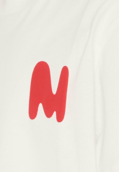 Maglietta bianca con una grande e audace grafica rossa a forma di lettera "M" stilizzata. Texture liscia e vestibilità casual.