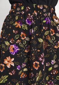 Black floral skirt featuring a stretchy waistband, with multicolored flowers in purple, orange, and green on a textured fabric background.