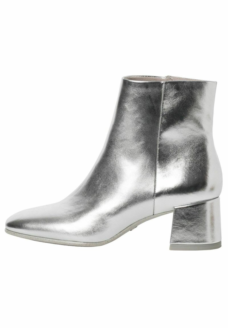 Glanzend zilveren enkelboot met spitse neus, lage blokhak en een gladde metallic afwerking, afgebeeld vanuit de zijkant op een witte achtergrond.