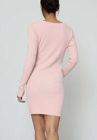 Robe à manches longues en rose clair, côtelée. Silhouette ajustée avec un col rond et des fentes latérales à l'ourlet pour faciliter le mouvement.
