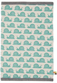 Copertura in tessuto di cotone con motivo a spirali teal ripetuto su uno sfondo crema chiaro. Rifinita con un bordo in tessuto grigio lungo il bordo superiore.