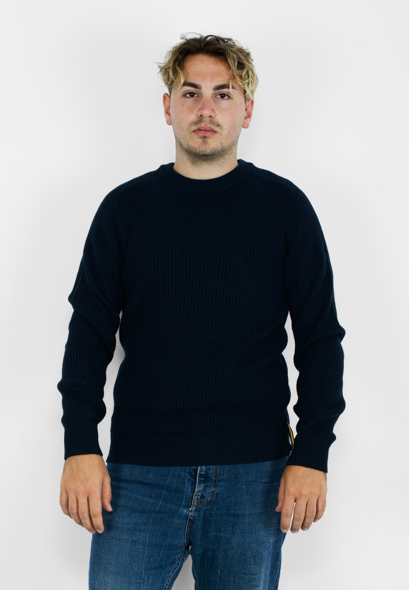 Maglione a coste blu scuro con maniche lunghe, scollo rotondo e vestibilità aderente, abbinato a jeans in denim blu.
