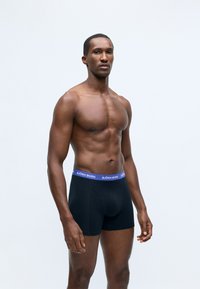 Black boxer briefs with a purple waistband, featuring the brand name "BJÖRN BORG" prominently displayed. Smooth fabric and fitted design.