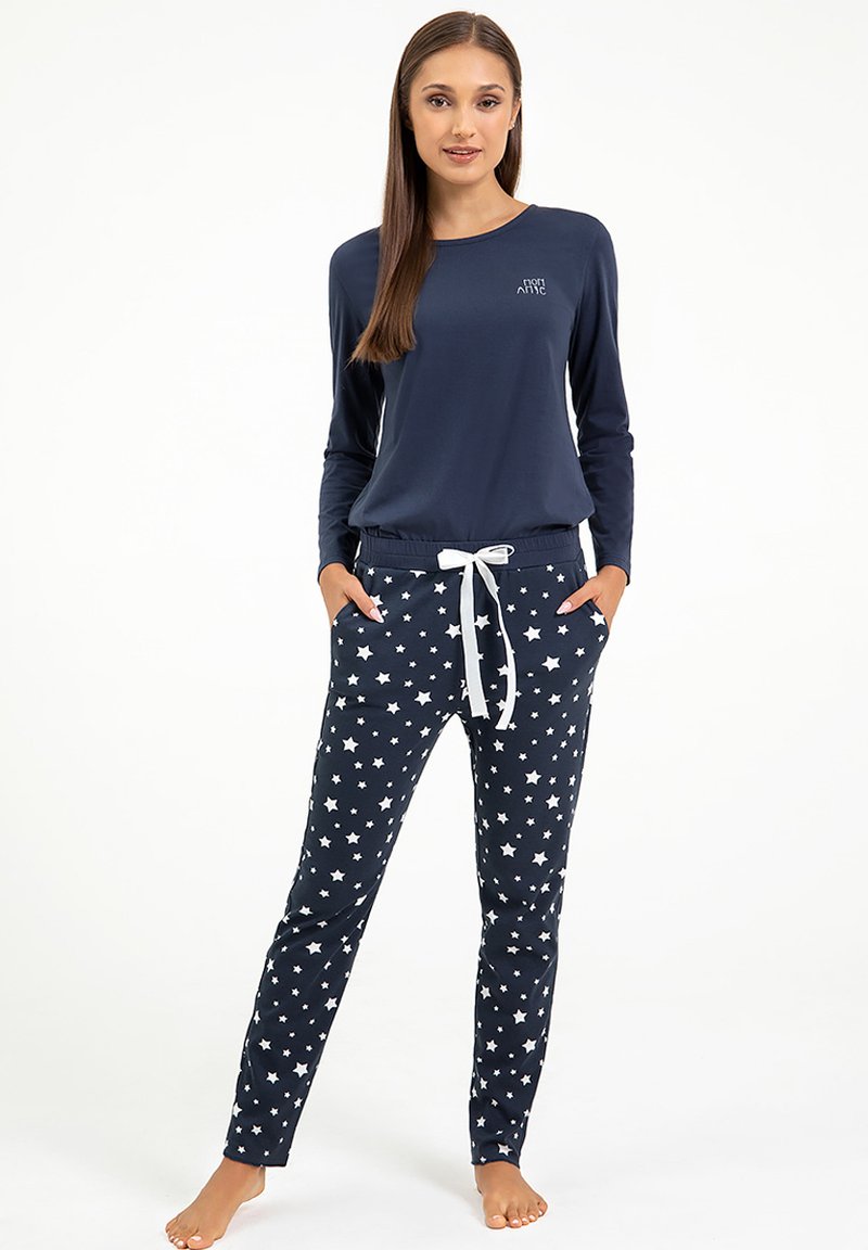 Granatowa bluzka z długim rękawem z logo, zestawiona z granatowymi spodniami piżamowymi w białe gwiazdy i białym sznurkiem w pasie.