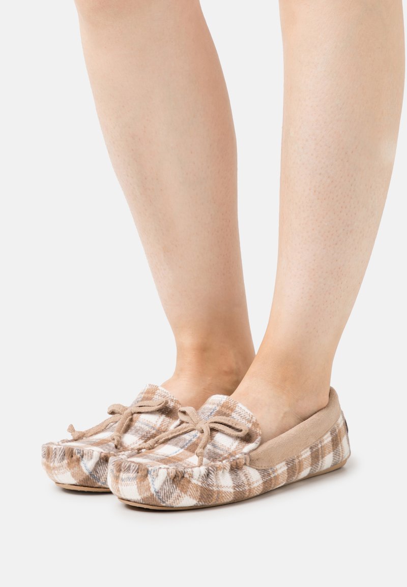 Beige and brown plaid slippers featuring a soft fabric upper, tied bow accents, and a flexible sole. Ideal for indoor use.
