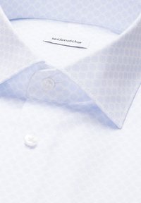 Chemise blanche à motif hexagonal subtil, col pointu, deux boutons blancs et étiquette "seidensticker" à l'intérieur du col.
