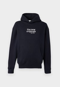 Kapuć sweatshirt u tamnoplavoj boji s prednjim džepom. Na grudima se nalazi bijeli izvezeni natpis "nova izvorna jazz klub".