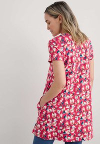 Bloemen tuniek in een vibrante roze tint, met korte mouwen, een ontspannen pasvorm en zijzakken. Het patroon bevat kleurrijke bloesems en bladeren.