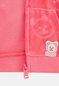 Felpa con zip rosa caratterizzata da un motivo testurizzato di orsetti, tessuto morbido, polsini a coste e etichetta di marca con logo dell'orso. Zip di un rosa abbinato.