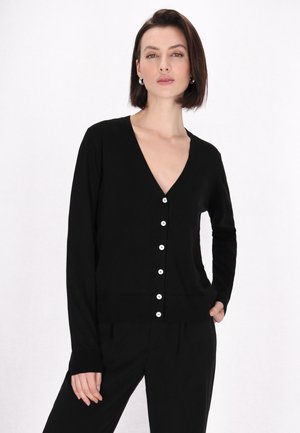 Zwarte cardigan met lange mouwen en een diepe V-hals, voorzien van witte knopen aan de voorkant en een ribbelrand. Gladde gebreide textuur.