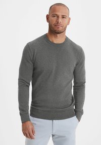 Grauer Rundhalsausschnitt-Pullover aus Strickstoff mit langen Ärmeln und gerippten Bündchen. Der untere Saum ist ebenfalls gerippt und sorgt für eine körpernahe Passform.