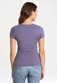Purple cotton t-shirt with short sleeves, fitted design, and smooth texture, paired with light blue denim jeans featuring back pockets.