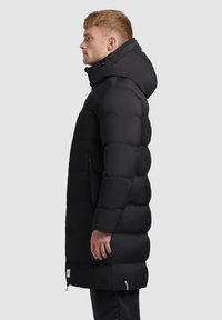 Black puffer coat with a hood, featuring a quilted design, zippered pockets, and a mid-length fit. Smooth texture and sleek silhouette.