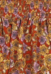 Bloemenjurk met een smocked lijfje, versierd met een oranje, gele en paarse bloemenprint op een textuurstof; met plissé rok detail.