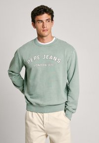 Zaļš kokvilnas džemperis ar ribotām aprocēm un apakšmalu, uz kura krūškurvja ir balta uzraksts "PEPE JEANS LONDON W11".