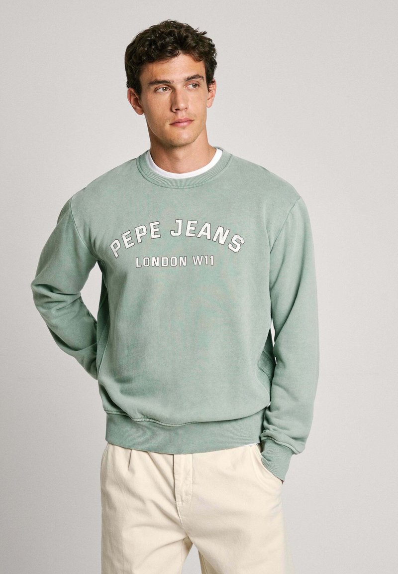 Zaļš kokvilnas džemperis ar ribotām aprocēm un apakšmalu, uz kura krūškurvja ir balta uzraksts "PEPE JEANS LONDON W11".