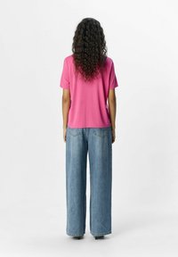 Pink short-sleeved t-shirt made of smooth fabric, paired with light blue wide-leg jeans featuring minimal stitching and a classic cut.