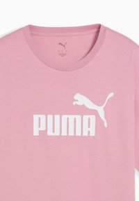 Lyserød bomulds T-shirt med korte ærmer, der har et hvidt Puma-logo og en springende katte design på fronten, rund halsudskæring.