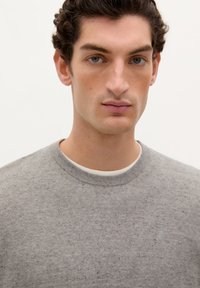 Grijze katoenen sweater met een ronde halslijn, gekenmerkt door een textuur gebreid patroon en een subtiel logo op de borst.