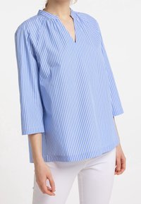 Ljusblå och vit randig blus med V-ringning, 3/4-ärmar och avslappnad passform, tillverkad av ett mjukt tyg med subtil textur.