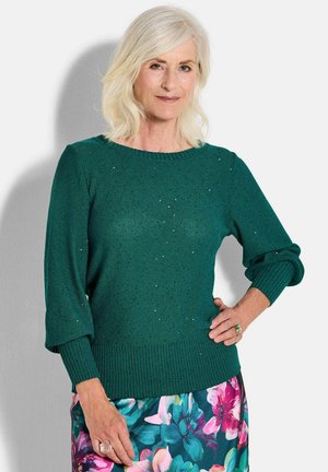 Dunkelgrüner Strickpullover mit geripptem Saum und breiten Ärmeln, der im gesamten Stoff dezente Funkeln aufweist.