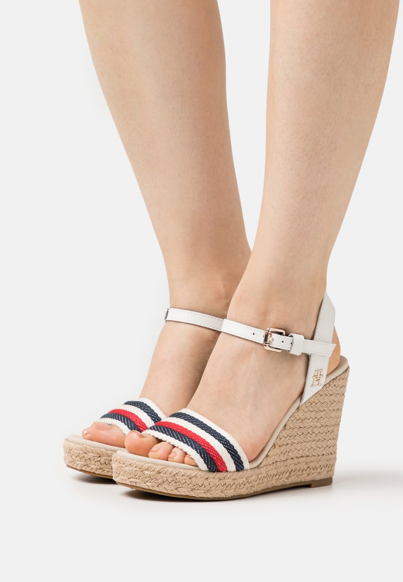 Sandali wedge bianchi con suola in juta, due cinturini intrecciati con strisce rosse e blu navy, e una cinghia alla caviglia con fibbia.