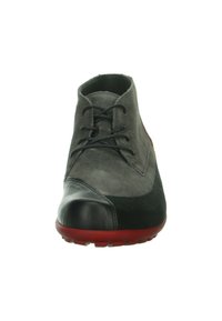 Grijze suede enkellaars met een zwarte leren neuskap, rode rubberen zool en zwarte veters. Beschikt over een gladde en gestructureerde oppervlakte.