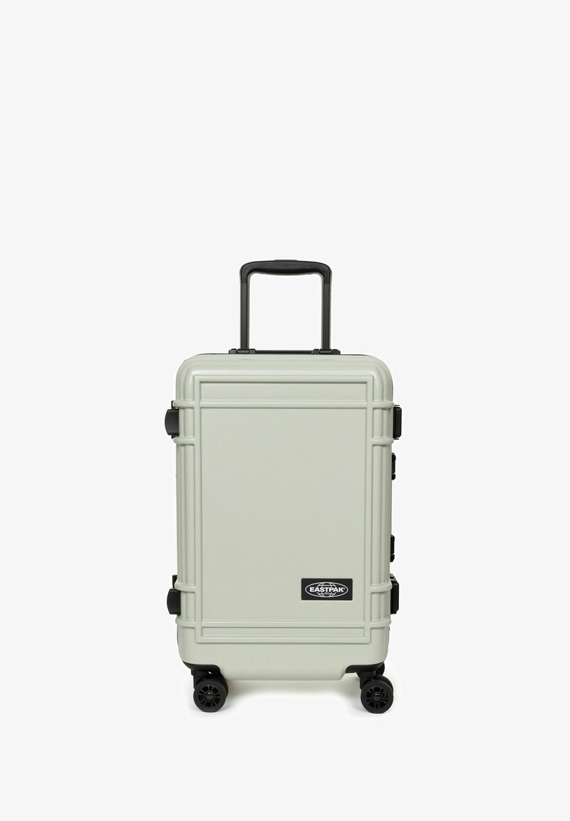 Tvrdý kufr ve světle šedé barvě s texturovaným povrchem, sklopným černým madlem a čtyřmi černými kolečky. Na přední straně je umístěno logo.