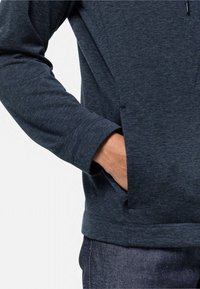 Felpa con cappuccio blu scuro, con una texture morbida, maniche lunghe e tasche laterali. Caratterizzata da una vestibilità comoda e polsini a coste.