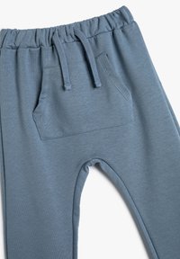 Blå joggingbyxor tillverkade av mjukt tyg, med elastisk midja och snörning, samt en enda framficka med en slät yta.