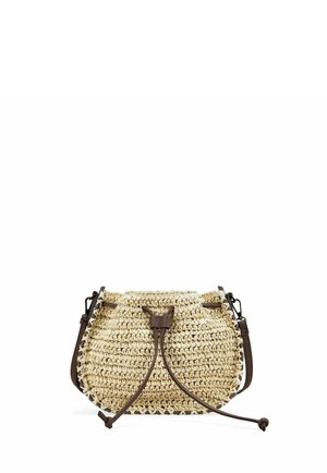 Bolso bandolera de paja beige tejido con cierre de cordón de cuero marrón oscuro y correa para el hombro sobre un fondo blanco.
