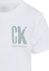 Camiseta de algodón blanca con un logo "CK" en verde menta y texto "Calvin Klein Jeans" en una tipografía moderna. Cuello redondo, mangas cortas.