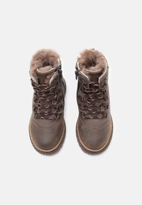 Une paire de bottes d'hiver en cuir marron avec doublure en fourrure, lacets épais et semelles robustes, présentée en vue de dessus sur un fond blanc.