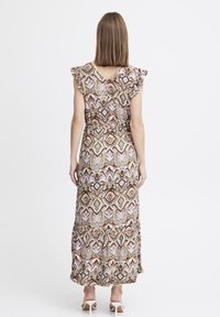 Robe maxi avec des manches ondulées, présentant un motif géométrique dans des tons terreux de brun, rose et vert, et un ourlet évasé et léger.