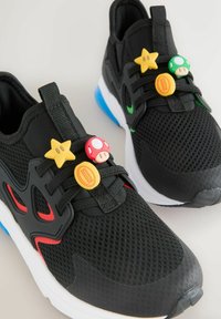 Black mesh sneakers featuring a white midsole and blue accents. Three decorative charms shaped like stars and mushrooms on the laces.