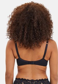 Reggiseno nero con spalline regolabili e rifinitura in pizzo. Presenta un tessuto liscio e una chiusura a gancio e occhiello sul retro.