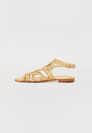 Gold leather sandal with a braided design, featuring an open toe, multiple straps, and a flat sole. Adjustable ankle strap included.