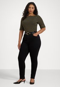 Čierne vysoké skinny džínsy s prednými vreckami, skombinované s priliehavým čiernym a žltým pruhovaným tričkom a čiernymi slingback topánkami na podpätku.