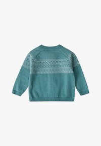 Pull en tricot turquoise avec un motif géométrique blanc sur les épaules, des manches raglan et des détails côtelés aux poignets. Texture douce.