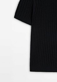 Pull noir à manches courtes en maille, avec un motif texturé vertical et un ourlet côtelé, présenté sur fond blanc.
