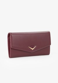 Burgundowa skórzana portmonetka o eleganckim prostokątnym kształcie, z złotym trójkątnym akcentem z przodu oraz teksturowaną powierzchnią.