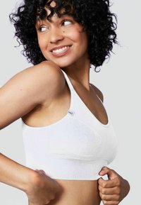 Reggiseno in tessuto elasticizzato bianco con spalline sottili, caratterizzato da un design testurizzato e un piccolo etichetta del marchio sul lato, che evidenzia una forma aderente.