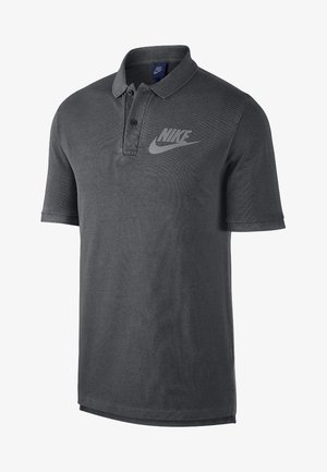 Dunkelgraues Nike-Poloshirt mit kurzen Ärmeln, geknöpftem Kragen und großem Nike-Logo auf der linken Brust.
