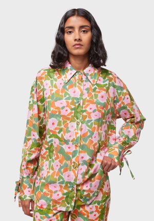 Chemise à manches longues avec un motif floral multicolore comprenant des nuances de rose, de vert et d'orange, dotée d'un col pointu et d'une fermeture à boutons.