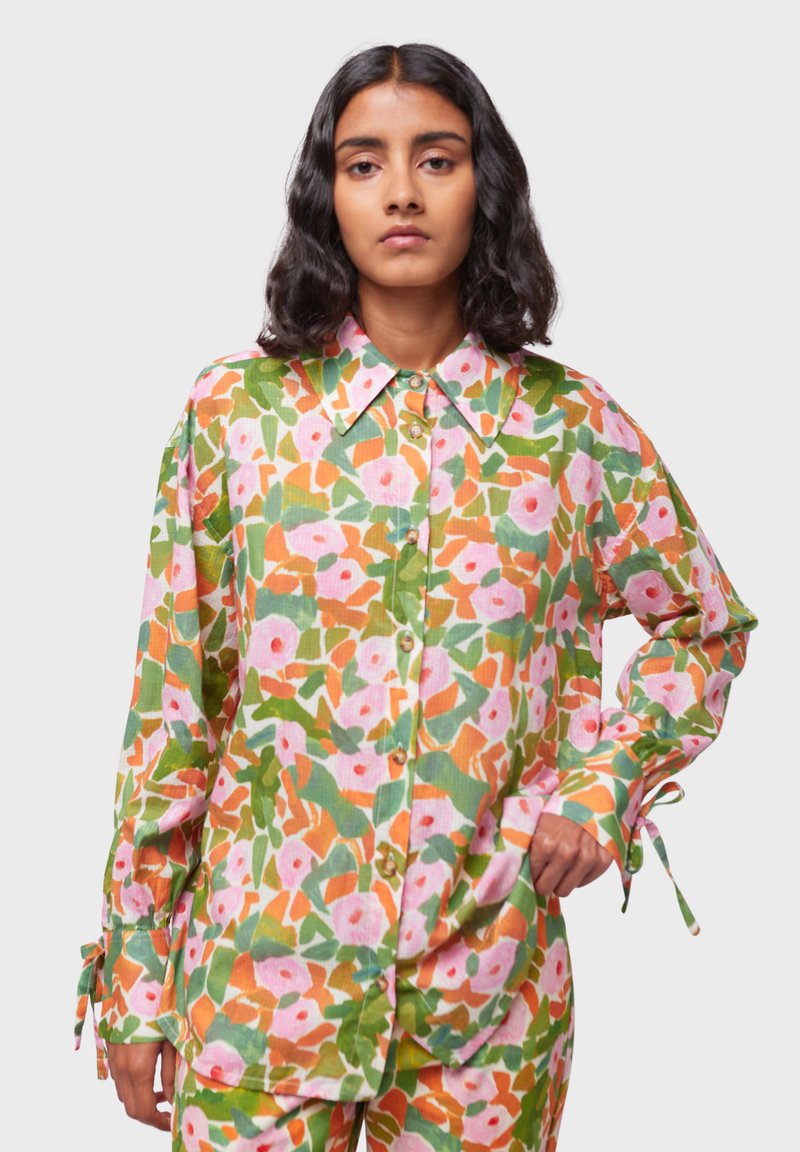 Camicia a maniche lunghe con un motivo floreale multicolore caratterizzato da tonalità di rosa, verde e arancione, con colletto a punta e chiusura con bottoni.