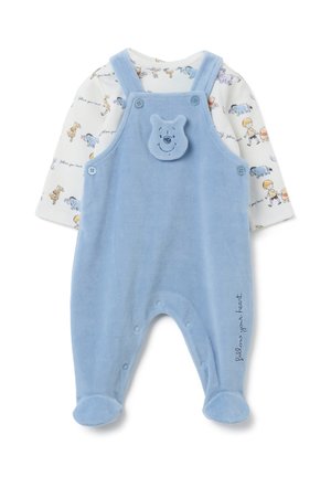 Lichtblauwe baby rompert met voetjes en knopenbandjes, met een lachend berengezicht op de borst, gelaagd over een witte lange mouw shirt met cartoonfiguren.