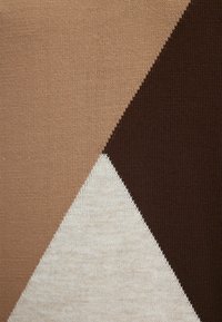 Tissu tricoté présentant des motifs géométriques en beige, crème et marron foncé. Texture lisse avec un blocage de couleur distinct et des bords nets.