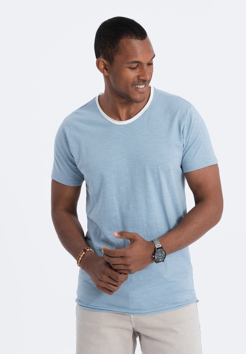 Lyseblå kortærmet T-shirt med hvid rund hals, lavet af blødt tekstil, parret med beige bukser.