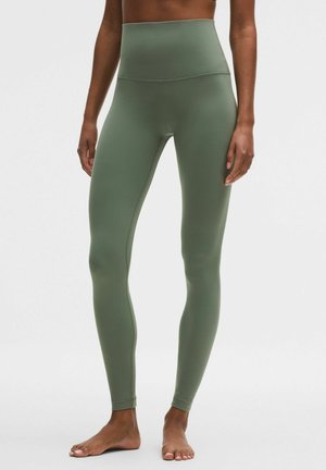 Vyötäröä korostavat, vartalonmyötäiset leggingsit oliivinvihreänä, valmistettu joustavasta kankaasta. Silkinpehmeät saumat ja nilkkapituisen mallin.