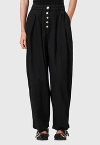 Pantalones de pierna ancha negros que presentan una cintura alta, cinco botones grandes y pliegues para mayor volumen. Fabricados en una tela suave.